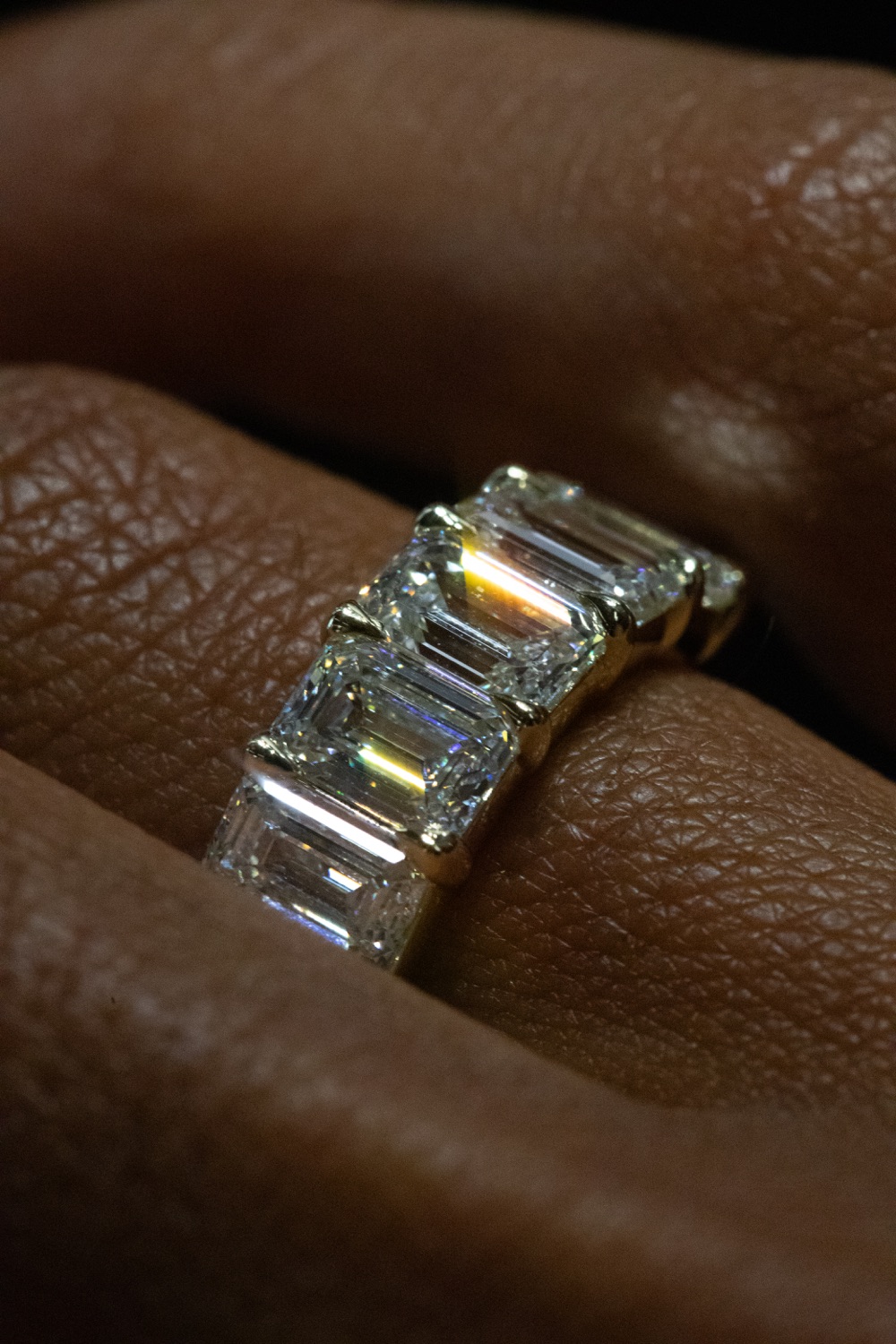 A cocktail ring set with a row of emerald-cut diamonds in yellow gold